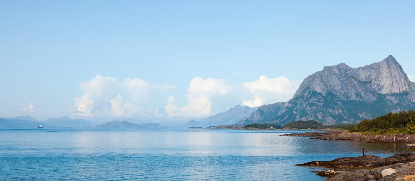 Kystlandskap ved Bodø med blått hav og fjell i bakgrunnen.
